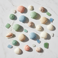 Shell-shaped wax melts in coastal colors on white marble with seashells and sea glass