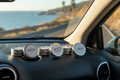 Aluminum tins with Black Ice, Mahogany Teakwood, and Volcano labels in car with coastal road view